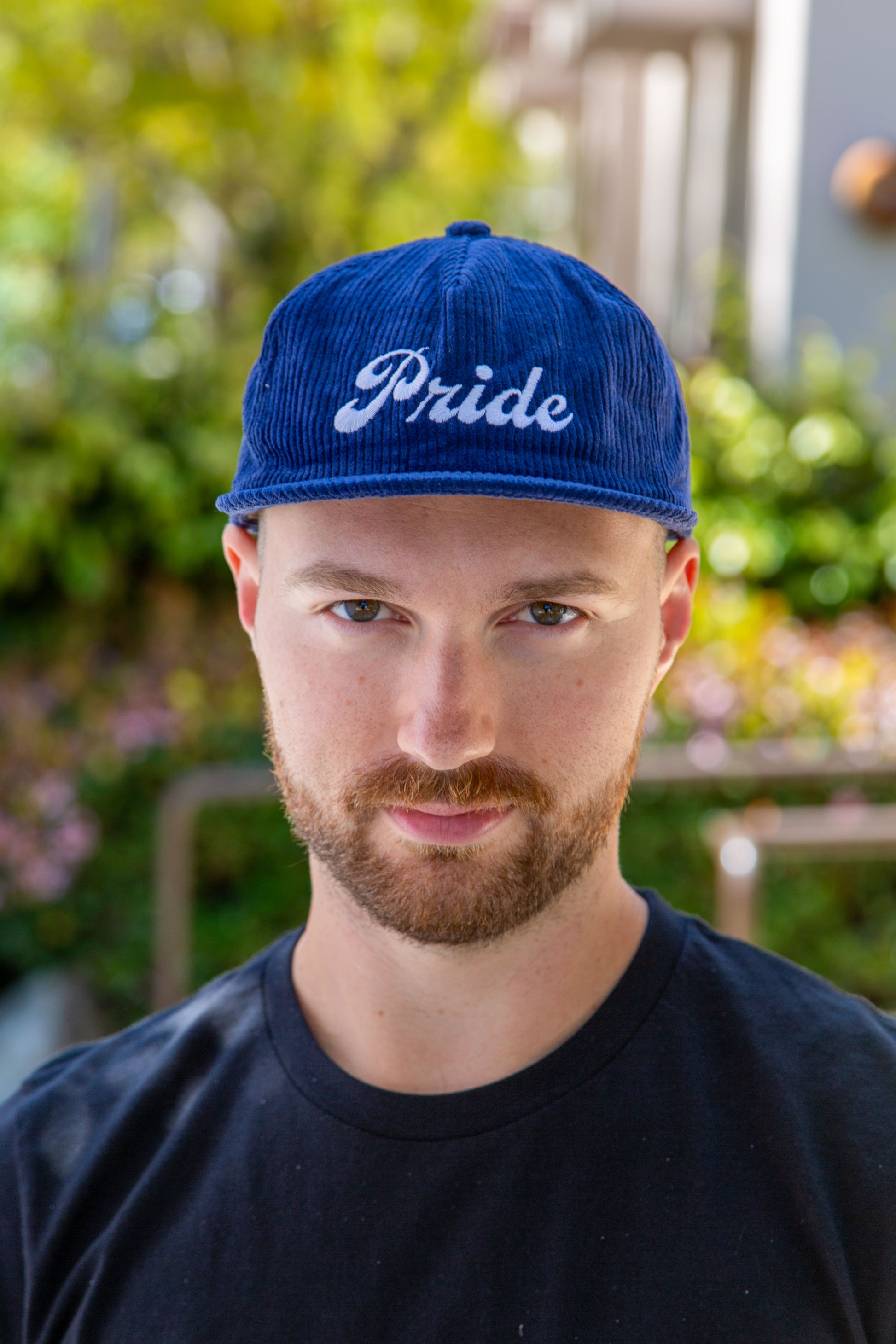 Person wearing the navy blue <Insert Material Type> hat with the text "Pride" on the front outside.