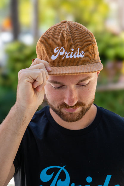 Person wearing the brown <Insert Material Type> hat with the text "Pride" on the front outside.