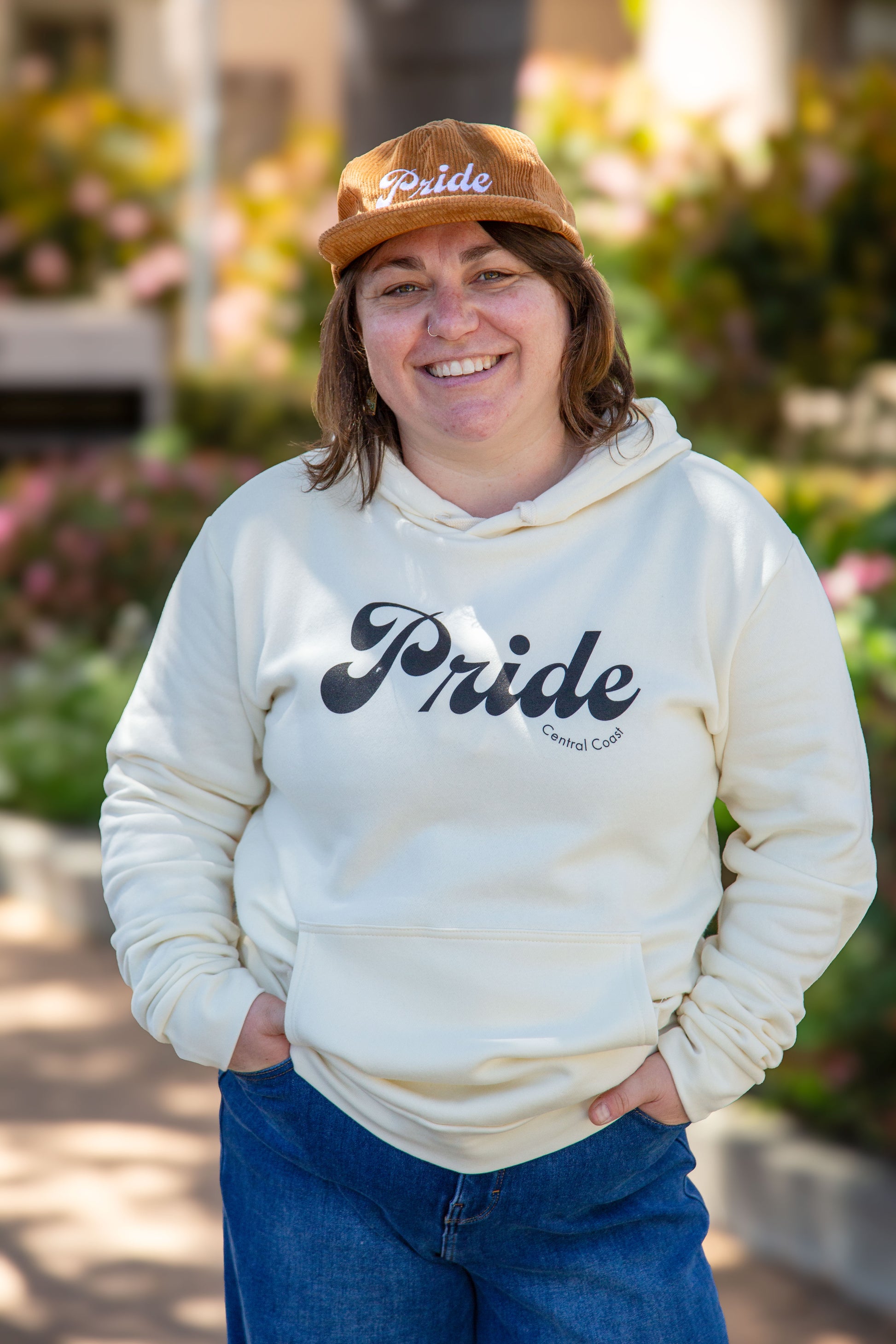 Person wearing the cream colored sweater with the text "Pride" and "Central Coast" below in smaller font.